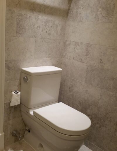 A modern toilet in a bathroom with beige tiled walls.
