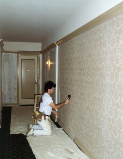 A person applying wallpaper in a corridor.