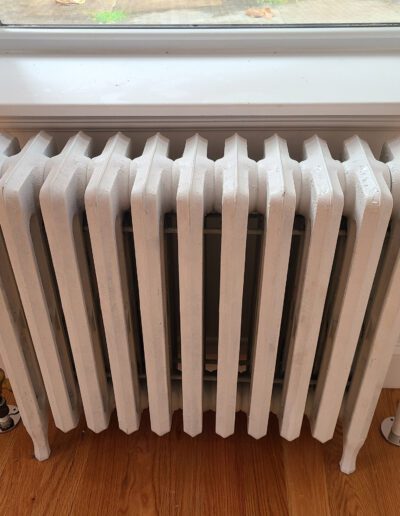 White cast-iron radiator beneath a window.