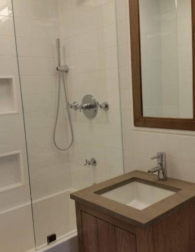 Modern bathroom interior with glass shower enclosure and wooden vanity.